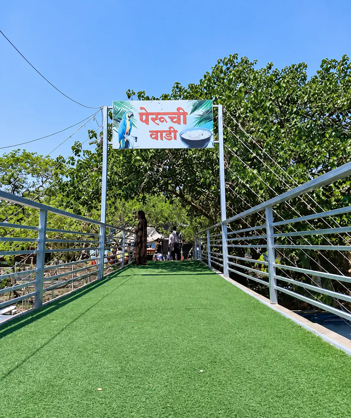 Grass-carpeted footbridge with a Peruchi Wadi sign